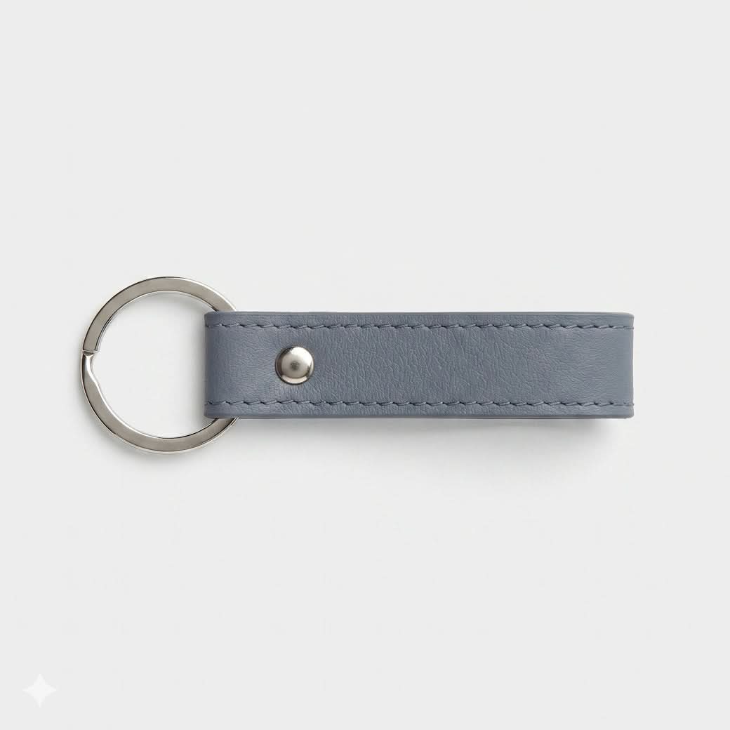 Llavero Maison Caviar Capri en color gris azulado con diseño elegante y detalles en piel sintética.