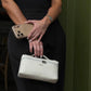 Bolso Giulia de Maison Caviar, bolso de mano elegante en cuero con detalles metálicos y asa superior, en color negro.