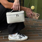 Bolso Giulia de Maison Caviar, bolso de mano en cuero con detalles elegantes y asa superior, sobre fondo neutro.
