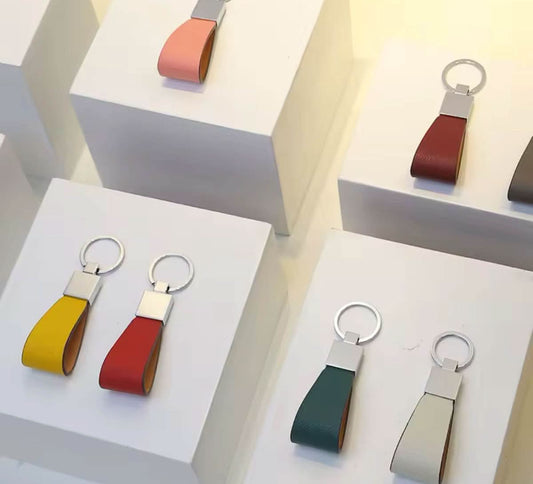 Llavero Maison Caviar Paolo con detalles en metal y diseño elegante, colgado de una mano con fondo neutro.