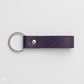 Llavero Maison Caviar Capri en color morado con diseño elegante y detalles en la superficie, para llaves y accesorios.