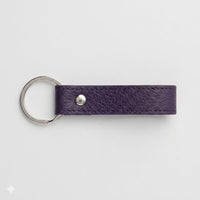 Llavero Maison Caviar Capri en color morado con diseño elegante y detalles en la superficie, para llaves y accesorios.